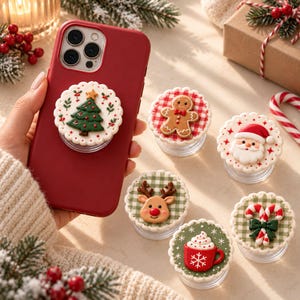 May include: A collection of round, scalloped-edge phone grips featuring holiday designs including a Christmas tree, a gingerbread man, Santa Claus, a reindeer, and a red mug with whipped cream and candy canes.