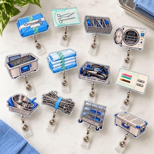 May include: A collection of twelve acrylic badge reels featuring illustrations of medical equipment, including surgical instrument trays, sterilization containers, wrapped sterile packs, a medical cart, and diagnostic monitors with blue and silver tones.