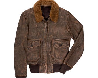 May include: A distressed brown leather bomber jacket with a shearling collar. The jacket features two front pockets with button closures, a zip-up front, and ribbed cuffs and hem. The jacket has a vintage, worn look.