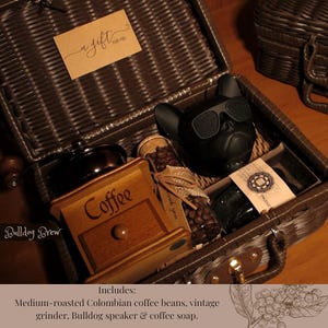 Peut inclure: Un panier-cadeau en osier marron rempli d'articles sur le th&egrave;me du caf&eacute;. Comprend un haut-parleur bouledogue noir avec des lunettes de soleil, un moulin &agrave; caf&eacute; en bois vintage, des grains de caf&eacute; et un petit bocal. Une &eacute;tiquette cadeau dit "a gift for you."