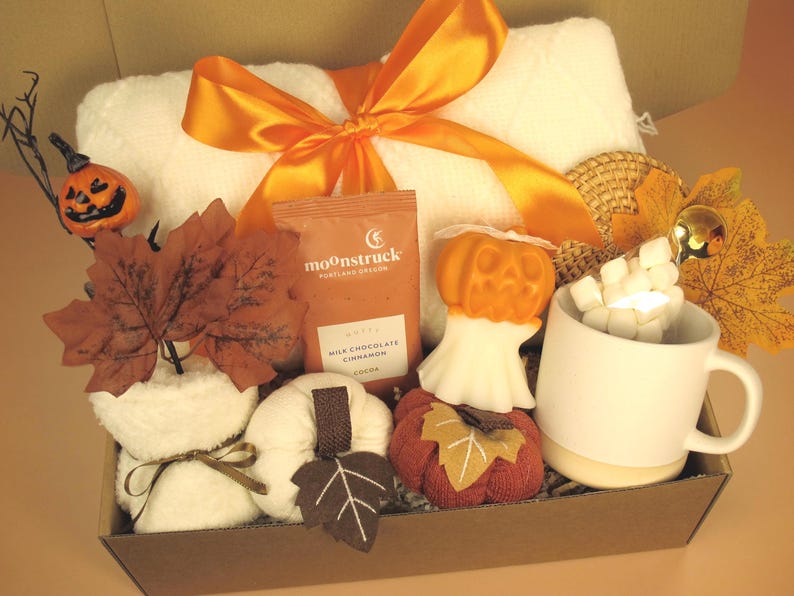 Puede incluir: Una cesta de regalo con art&iacute;culos tem&aacute;ticos de oto&ntilde;o. Incluye una toalla blanca con un lazo naranja, calabazas decorativas, una taza con malvaviscos, un paquete de cacao de chocolate con leche y canela Moonstruck y hojas de oto&ntilde;o.