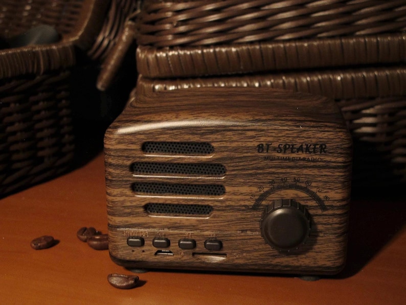 Peut inclure: Un petit haut-parleur BT de style r&eacute;tro avec une finition imitation bois. Le haut-parleur a un cadran, des boutons et le texte "BT SPEAKER MULTIMEDIA COMBINING". Des grains de caf&eacute; sont &eacute;parpill&eacute;s devant le haut-parleur.