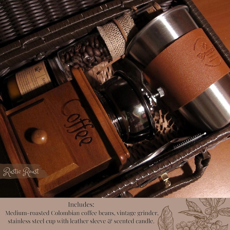 Peut inclure: Un panier en osier marron rempli d'articles li&eacute;s au caf&eacute;. Il comprend un moulin &agrave; caf&eacute; en bois, une tasse en acier inoxydable avec un manchon en cuir, un pot de grains de caf&eacute; et une bougie parfum&eacute;e. Le texte "Rustic Roast" est visible.