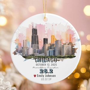 May include: A white ceramic ornament with a gold string, featuring a watercolor skyline of Chicago. The ornament includes the text "CHICAGO", "OCTOBER 12, 2025", "Marathon Finisher", "26.2", a name, and a time.