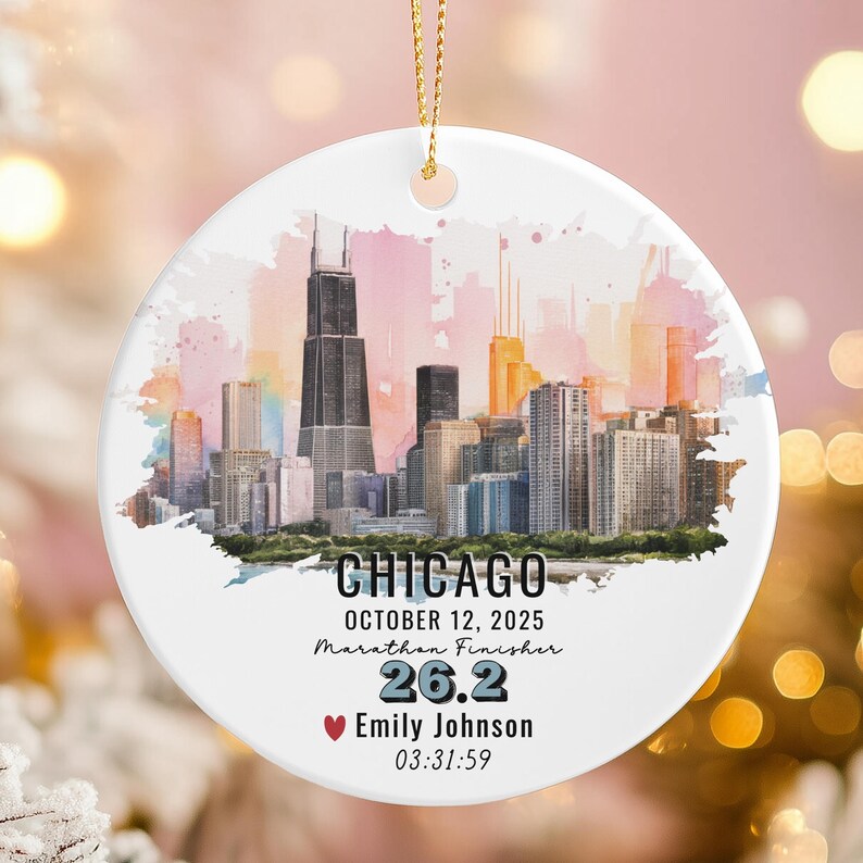 May include: A white ceramic ornament with a gold string, featuring a watercolor skyline of Chicago. The ornament includes the text "CHICAGO", "OCTOBER 12, 2025", "Marathon Finisher", "26.2", a name, and a time.