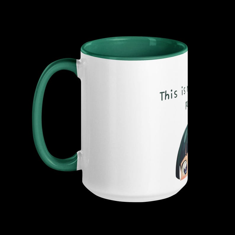 May include: White ceramic mug with a green handle and interior. The mug features an illustration of an anime character and the text "This is probably". The mug is set against a black background.