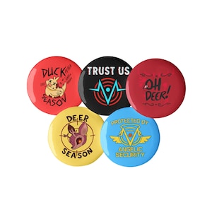 May include: A collection of five round pinback buttons. The buttons are red, black, yellow, and blue. Each button has a unique graphic and text, including "Duck Season," "Trust Us," and "Oh Deer!"