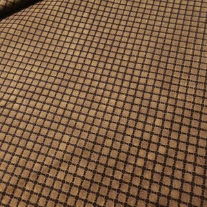 Peut inclure: Tissu marron avec un motif répétitif de cercles brun foncé reliés par des lignes, créant un motif quadrillé. Le tissu a un aspect texturé et une palette de couleurs chaudes et terreuses. Idéal pour la couture et les projets d'artisanat.