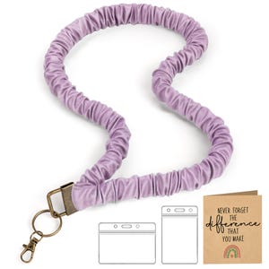 May include: A lilac velvet lanyard with a bronze-coloured clasp and key ring. Includes a clear plastic ID holder and a card with the text "NEVER FORGET THE difference THAT YOU MAKE" and a rainbow.