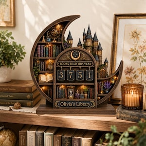 May include: A crescent moon-shaped wooden bookshelf display featuring a miniature castle, illuminated shelves with tiny books, an hourglass, and a mechanical counter with the text BOOKS READ THIS YEAR and the name Olivia's Library.
