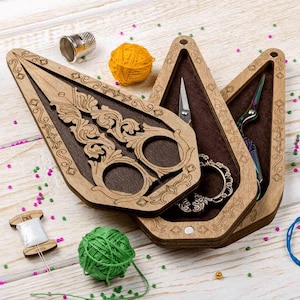 May include: Wooden sewing kit with ornate scissors, a thimble, and spools of thread. The kit includes a decorative wooden case with a dark brown interior, holding various sewing tools and colorful yarn balls. A perfect gift for a seamstress.