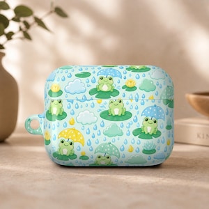 May include: A light blue case for wireless earbuds, adorned with a repeating pattern of cartoon frogs, umbrellas, clouds, and raindrops. The case has a rounded rectangular shape with a small loop on the side. The overall design is whimsical and colorful.