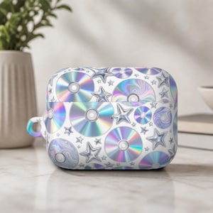 May include: A white AirPod case featuring a pattern of holographic CDs and silver stars. The case has a rounded rectangular shape with a small loop on the side for attaching a lanyard or clip.