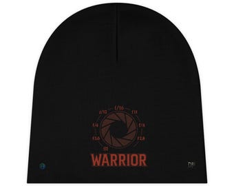 Può includere: Berretto nero con un design a diaframma marrone, indicazioni di apertura e la parola "WARRIOR" in rosso. Un berretto semplice e tinta unita, adatto a vari stili e occasioni.
