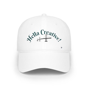 Puede incluir: Gorra de béisbol blanca con el texto "Hella Creative!" en verde azulado sobre una ilustración en blanco y negro de un puente. La gorra tiene una visera curva y un pequeño logotipo en el lateral.