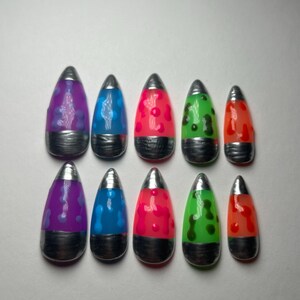 May include: Ten lava lamp-style nail art designs. Each nail has a silver tip, a black base, and a swirling design in purple, blue, pink, green, and orange. The nails are arranged in two rows of five, evoking a retro aesthetic.