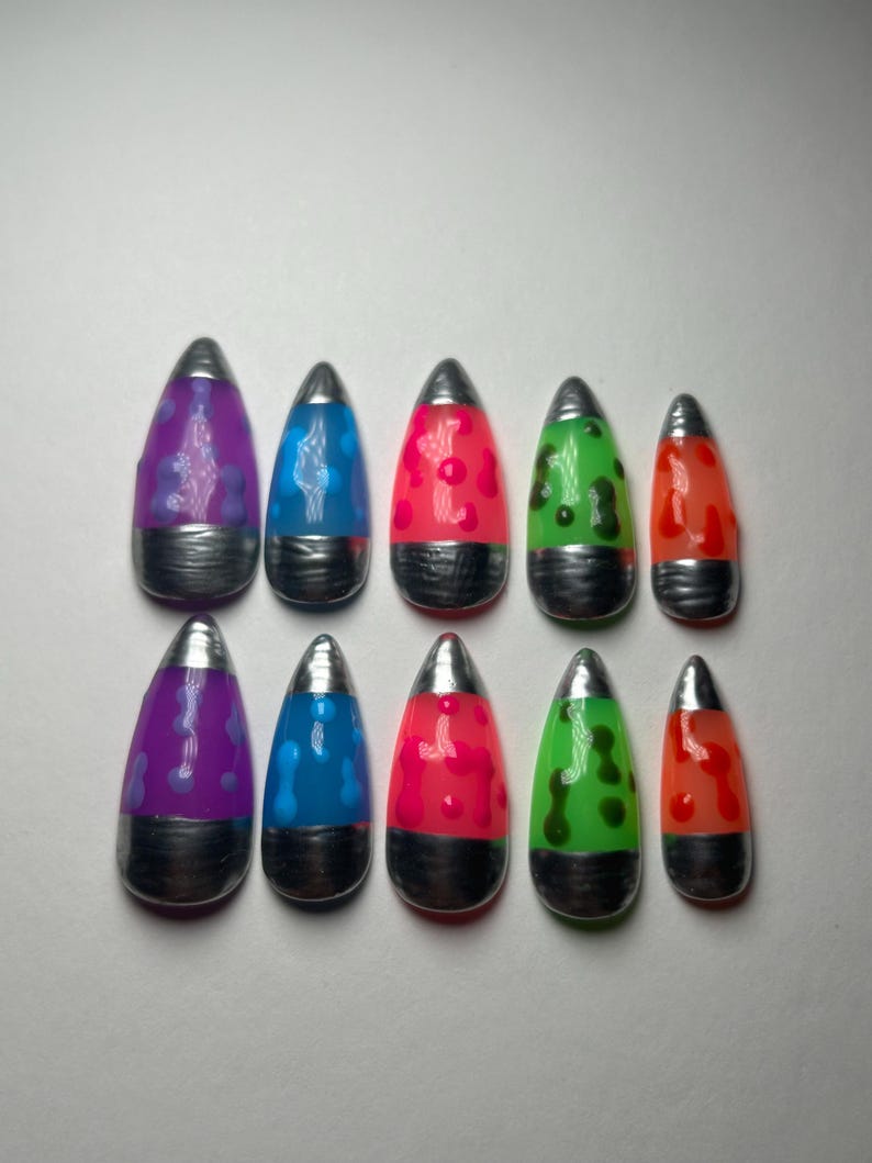 May include: Ten lava lamp-style nail art designs. Each nail has a silver tip, a black base, and a swirling design in purple, blue, pink, green, and orange. The nails are arranged in two rows of five, evoking a retro aesthetic.