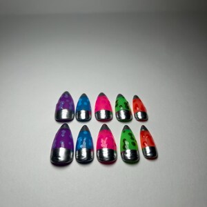May include: A collection of ten brightly coloured false nails. Each nail has a silver base and a vivid top in shades of purple, blue, pink, green, and red. The nails are decorated with various patterns and designs.