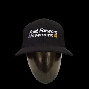 Puede incluir: Gorra de b&eacute;isbol negra con el texto "Fast Forward Movement" bordado en blanco y amarillo. La gorra tiene una visera curva y se muestra sobre una cabeza de maniqu&iacute; sobre un fondo negro.