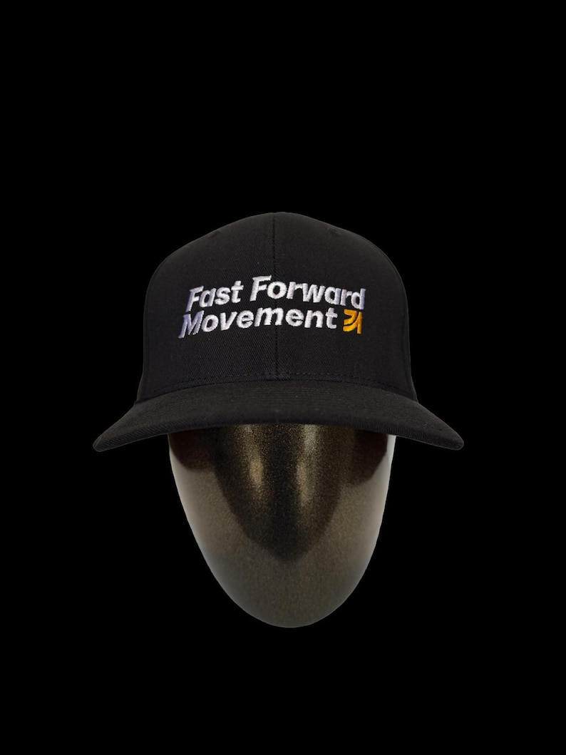 Puede incluir: Gorra de b&eacute;isbol negra con el texto "Fast Forward Movement" bordado en blanco y amarillo. La gorra tiene una visera curva y se muestra sobre una cabeza de maniqu&iacute; sobre un fondo negro.