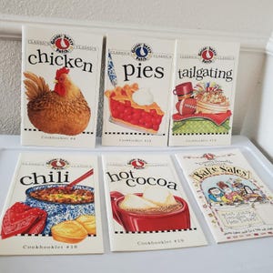 May include: Six Gooseberry Patch softcover cookbooks featuring illustrated covers with titles including Chicken, Pies, Tailgating, Chili, Hot Cocoa, and Bake Sales. Each booklet displays thematic food graphics and specific issue numbers.