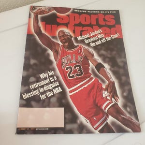 May include: A January 25, 1999 Sports Illustrated magazine cover featuring Michael Jordan in a red Chicago Bulls jersey with the number 23. The text reads Michael Jordan's Greatest Hits On and off the Court and Why his retirement is a blessing.