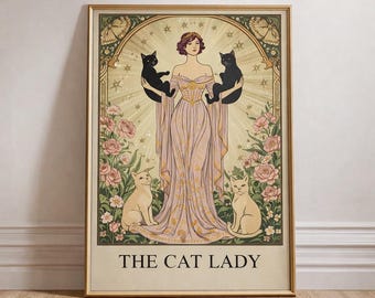 May include: A framed art print featuring a woman in a flowing gown holding two black cats, with two cream-colored cats at her feet. The artwork has a vintage style with floral and star accents, and the text "THE CAT LADY" at the bottom.