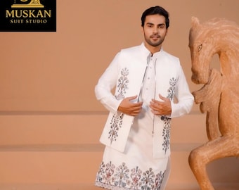May include: A white suit with floral embroidery, including a long-sleeved tunic, vest, and trousers. The suit is worn with brown sandals. The image includes the text "MUSKAN SUIT STUDIO" in a black box.