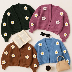 Puede incluir: Cuatro cárdigans abiertos en varios colores: verde oscuro, malva, marrón y azul claro. Cada suéter está adornado con aplicaciones de margaritas blancas y amarillas. Un libro, gafas de sol, una taza de café y un bolso también están en la imagen.