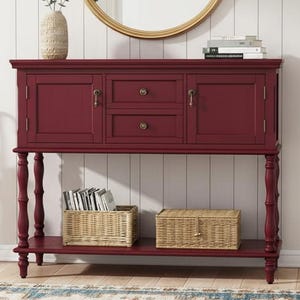 May include: A burgundy console table with two drawers and two cabinet doors, topped with a vase, books, and a gold-framed mirror. Two wicker baskets sit on the lower shelf. A rug and umbrella stand are in the foreground.