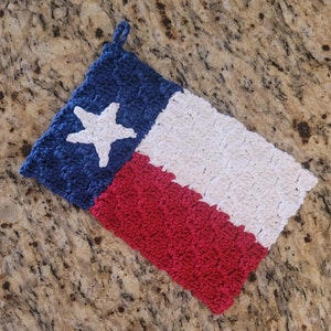 May include: Crocheted Texas flag dishcloth in red, white, and blue with a white star in the blue corner.