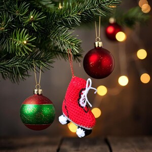 May include: Christmas tree ornaments, including a red crocheted roller skate with white laces and wheels, and two round ornaments. One ornament is red with glitter, and the other is green and red with a decorative pattern.