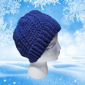 May include: A blue crocheted beanie hat on a white mannequin head. The hat is made with a textured stitch and has a slouchy fit.