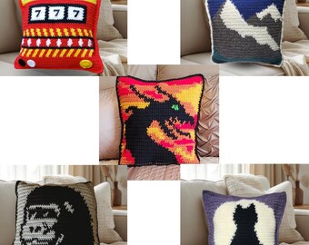 May include: A collection of five square crochet pillows featuring diverse designs: a red slot machine with 777, a blue mountain landscape, a black dragon on a yellow and orange background, a black gorilla head, and a black cat silhouette on a moon.