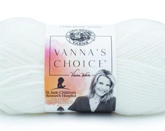 May include: A skein of Lion Brand Vanna's Choice yarn in white. The label features the brand name, a portrait of Vanna White, and the St. Jude Children's Research Hospital logo. The yarn is a soft, solid color.