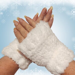May include: White, fluffy wrist warmers. The wrist warmers are made of a soft, textured material. The background is a light blue with snowflakes.