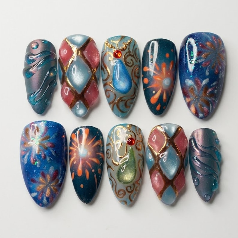 May include: A set of ten artificial nails with various designs. The nails feature a range of colors, including blue, pink, and gold, with patterns such as fireworks, geometric shapes, and abstract swirls. Each nail has a glossy finish.
