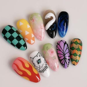 May include: A collection of ten artificial nails, each with a unique design. The designs include checkered patterns, floral motifs, flame graphics, and character illustrations. Colors range from black and green to vibrant oranges and pinks.