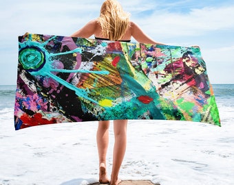 May include: A colourful beach towel with abstract paint splatters in shades of blue, green, yellow, red, pink, and black. The towel is draped over a person's shoulders.