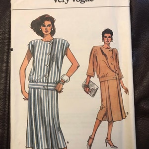 May include: A sewing pattern for a dress and jacket. The pattern is for sizes 8-10-12. The dress is striped and has a button-up front. The jacket is solid brown and has a button-up front. The pattern is called "Very Easy Very Vogue" and the pattern number is 9310.