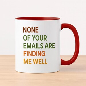 Puede incluir: Taza de cerámica blanca con interior y asa rojos. La taza presenta el texto "NONE OF YOUR EMAILS ARE FINDING ME WELL" en letras marrones, verdes, naranjas y amarillas.