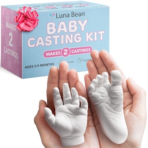 May include: A baby casting kit with a light blue box featuring the text "Luna Bean BABY CASTING KIT." The kit includes a pink bow and makes two castings. A white hand and foot casting are held in open hands. Ages 0-9 months.
