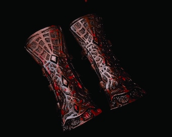 May include: Pair of intricately designed, brown and red arm bracers with geometric and diamond patterns. The bracers have a metallic appearance and are set against a black background. The image also includes a logo and QR codes for Instagram and YouTube.