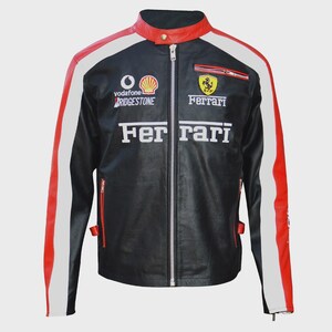 May include: A black racing jacket featuring red and white stripes along the sleeves and collar. The front displays the Ferrari logo, the word Ferrari, and sponsor logos for Vodafone, Shell, and Bridgestone. It has a full-length silver zipper.