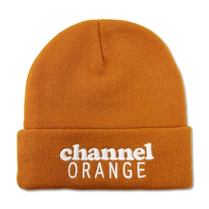 以下が含まれることがあります： オレンジ色のビーニー帽。白い文字で「channel ORANGE」と刺繍されています。ニット素材で、折り返しのつばが付いています。暖かくカジュアルなアクセサリーです。