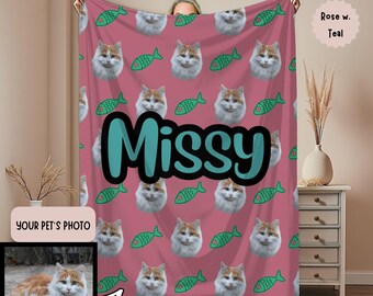 May include: A personalized pink blanket featuring a cat's face and green fish illustrations. The name "Missy" is displayed in large teal letters. A photo of the cat is shown in the lower left corner. The blanket is a custom pet gift.