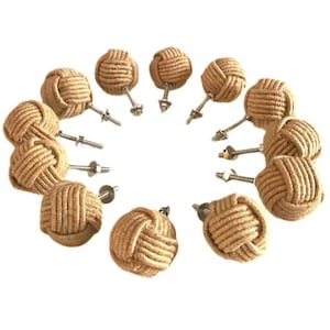 May include: A collection of twelve decorative cabinet knobs. Each knob features a spherical design made of tightly wound natural-colored rope. The knobs are attached to metal hardware with screws and washers, suitable for furniture or decor.
