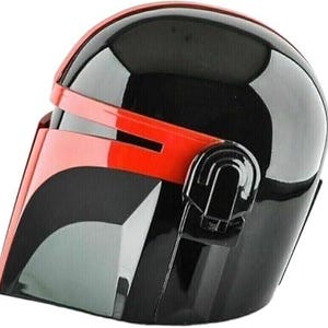 Pode incluir: Um capacete preto e vermelho com acabamento brilhante. O capacete apresenta uma viseira e detalhes vermelhos, com uma viseira escura. O design lembra um personagem com tema espacial.