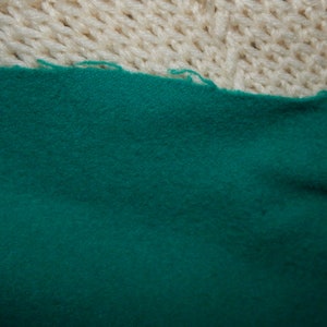 May include: Close-up of a dark teal fabric with a soft, fuzzy texture.