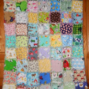 May include: A colorful patchwork quilt with a farm animal theme. The quilt is made of squares of different fabrics, each with a different farm animal or farm-related design. The quilt is edged with a white ruffle.
